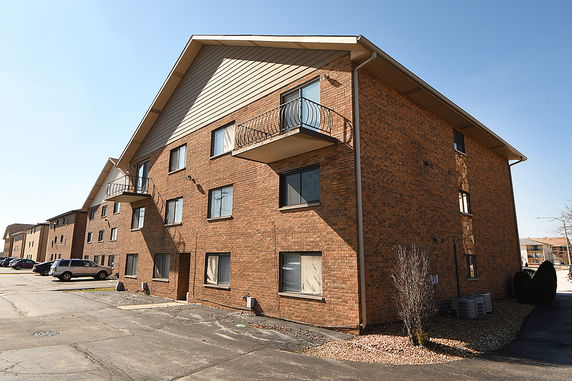Front view of a multi-story brick apartment building with balconies.