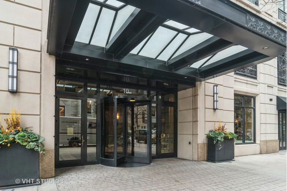 Front view of a building entrance with a glass canopy and revolving door.