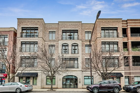 Front view of a multi-story brick building with large windows and balconies.