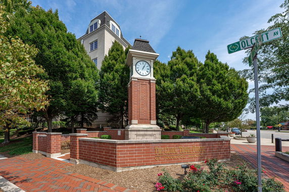 Front view of a multi-story building with a clock tower structure in the foreground.