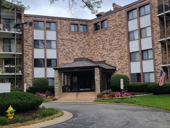 Front view of a multi-story brick building with balconies and an entrance canopy.