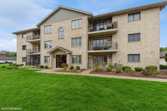Front view of a three-story apartment building with a brick exterior and multiple balconies.