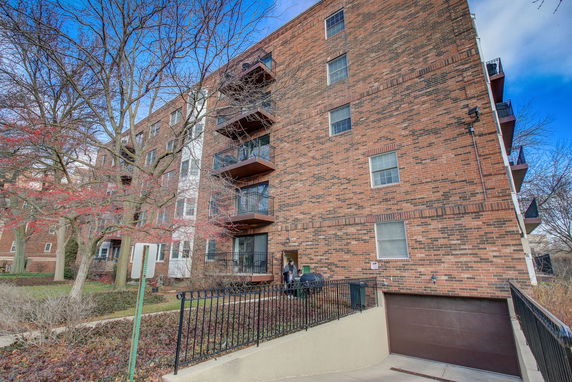Front view of a multi-story brick apartment building with balconies.