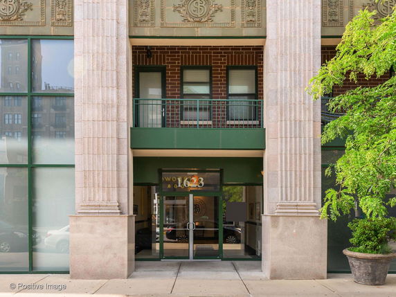 Front view of a building entrance with columns and green accents.