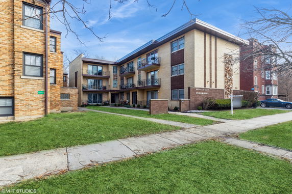 Front view of a three-story condominium building with brick exterior and balconies.