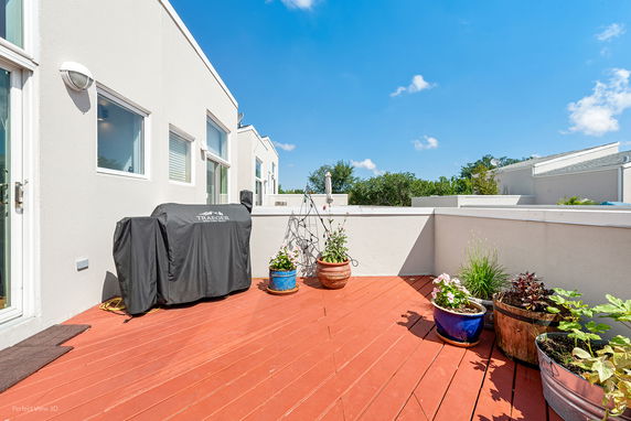 Rooftop area with potted plants and a barbecue grill.