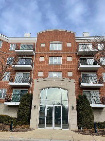 Front view of a multi-story brick apartment building with balconies.
