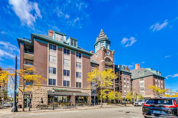 Front view of a multi-story brick building with a tower feature and street-level businesses.