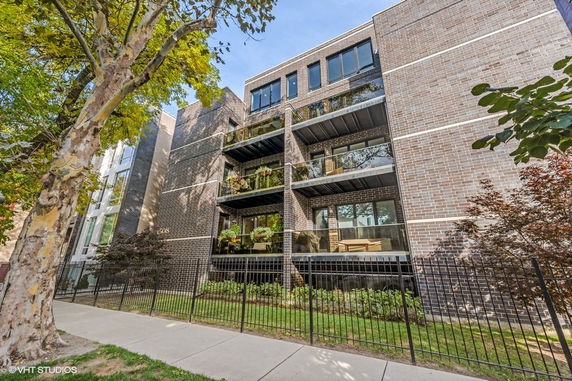 Front view of a multi-story brick apartment building with balconies.