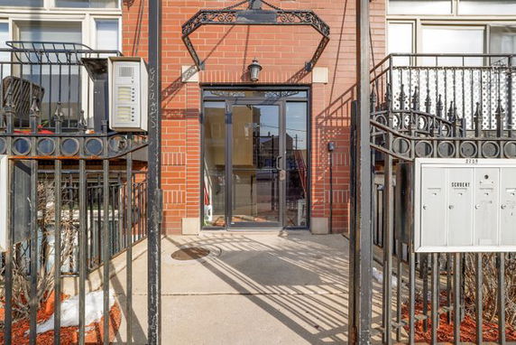 Front view of a building entrance with a glass door and red brick facade.