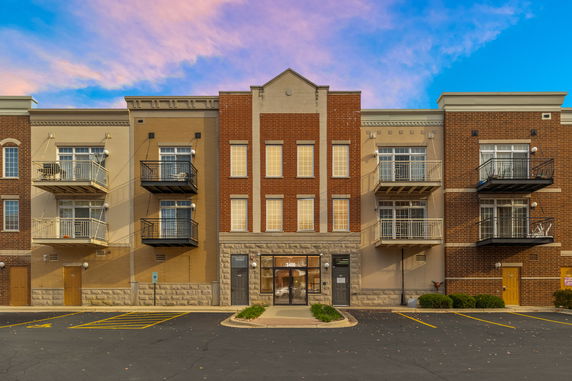 Front view of a three-story building with brick and beige facade, featuring small balconies.