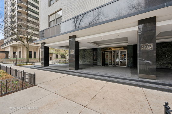 Front view of a multi-story building entrance with large pillars and a covered entryway.