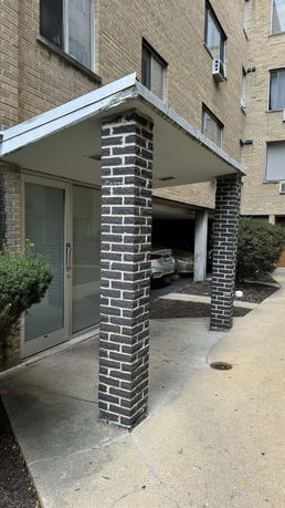 Front view of a building entrance with brick columns and an overhang.