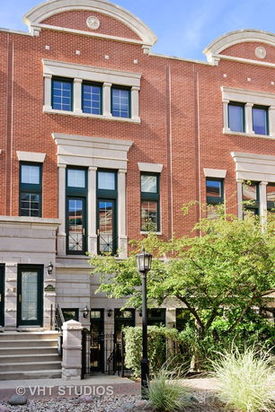 Front view of a multistory brick building with large windows and a staircase leading to the entrance.