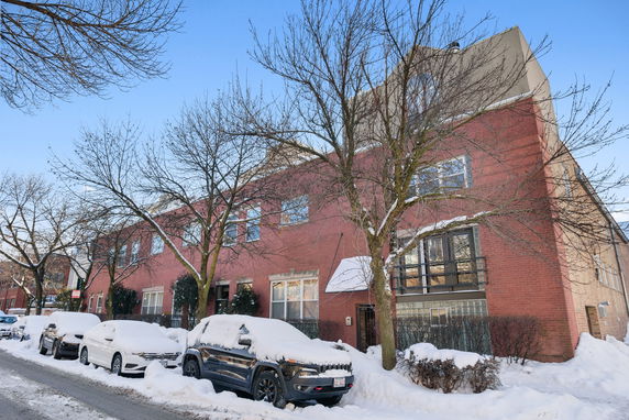 Front view of a row of red brick townhouses in a snowy environment.