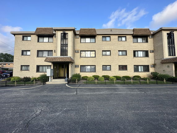Front view of a multi-story residential building with brick exterior and a central entrance.