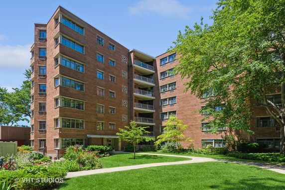 Front view of a multi-story brick apartment building with multiple balconies.