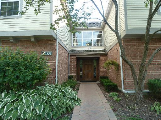 Front view of a two-story building entrance with brick and siding exterior.