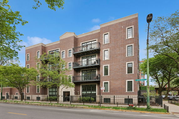 Front view of a multi-story brick apartment building with balconies.