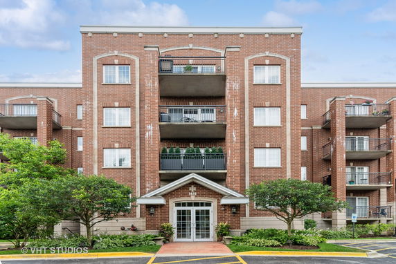 Front view of a multi-story brick apartment building with balconies.