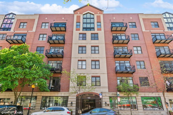 Front view of a multi-story brick apartment building with balconies.