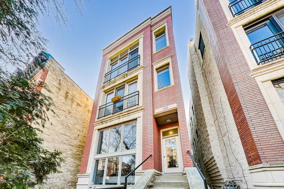 Front view of a multi-story brick building with balconies and windows.