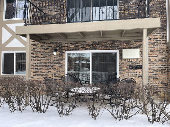 Front view of a brick building with a patio and balcony.