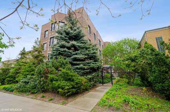 Front view of a multi-story brick building with surrounding greenery.