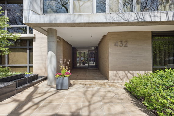 Front view of a building with a tiled walkway and planter, showing part of its facade and entrance.