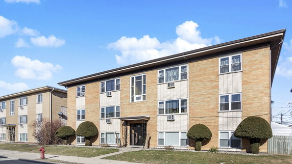 Front view of a two-story brick apartment building with multiple windows and a central entrance.