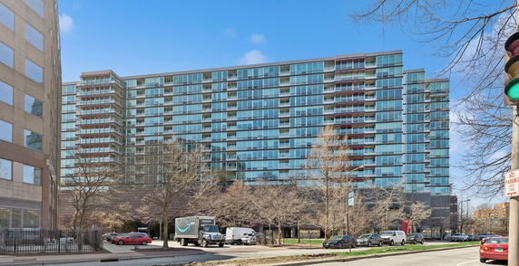 Front view of a large multi-story modern apartment building with glass facade.