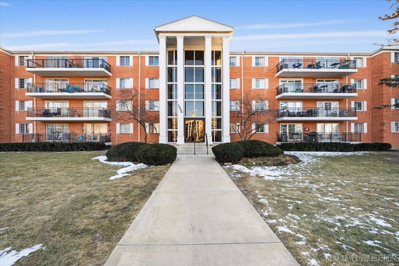 Front view of a multi-story building with balconies and a central entrance.