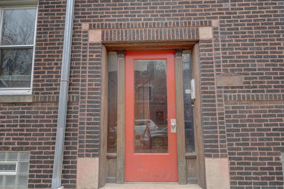 Front view of a building with a red entrance door and brick exterior.