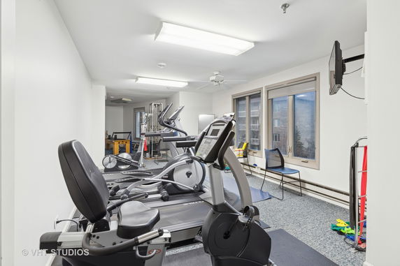 Indoor gym area with exercise equipment and windows.