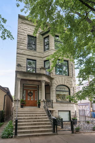 Front view of a multi-story house with stone facade and stairway entrance.