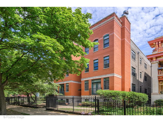 Front view of a multi-story brick building with a fenced yard.