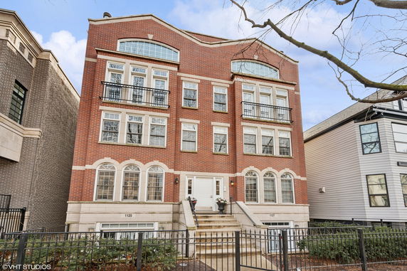 Front view of a multi-story brick building with multiple windows and entrance steps.