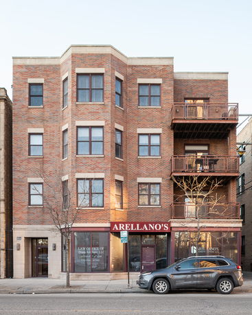Front view of a multi-story brick building with commercial offices on the ground floor.