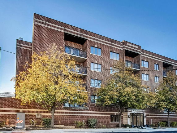 Front view of a multi-story brick apartment building with balconies.