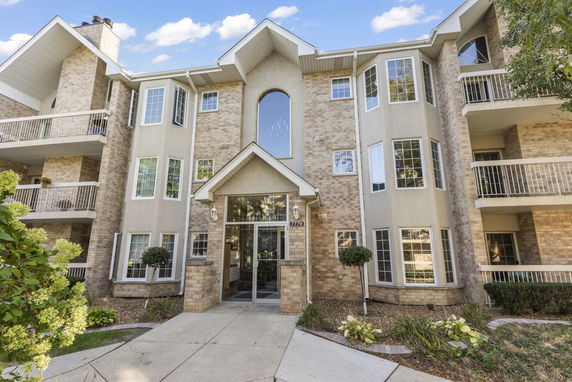 Front view of a multi-story residential building with balconies and a central entrance.