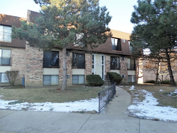 Front view of a multi-story apartment building with brick facade and balcony areas.
