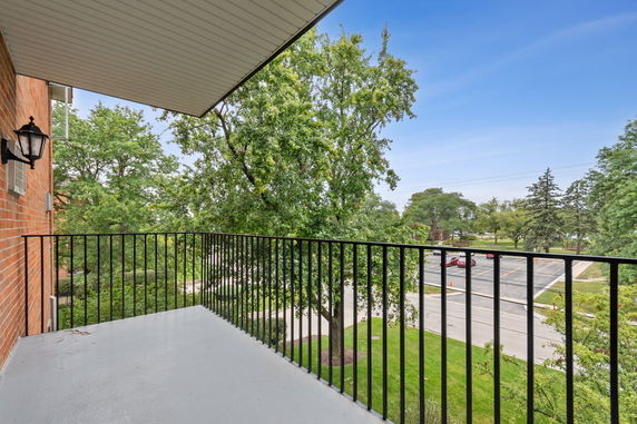 View from a balcony overlooking trees and a parking lot.