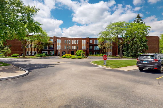 Front view of a multi-story brick building with white-framed windows and trees nearby.