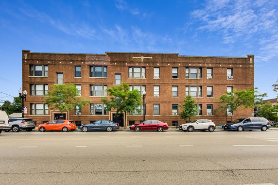 Front view of a three-story brick apartment building with multiple windows.