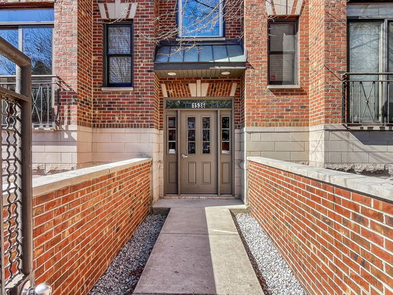 Front view of a building entrance with brick facade and a pathway leading to the door.