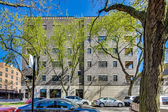 Front view of a multi-story brick building with large windows.
