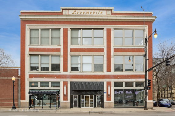 Front view of a multi-story brick building with large windows.