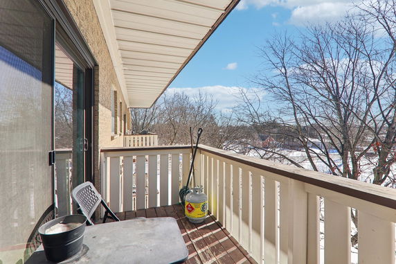Balcony view overlooking a snowy landscape with trees and clear blue sky.