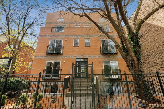 Front view of a multi-story brick residential building with balconies.