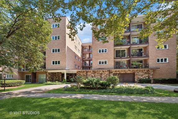 Front elevation view of a multi-story apartment building with balconies and brick exterior.